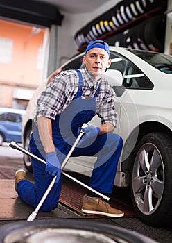 Professional auto mechanic screwing the wheel
