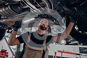 Professional auto mechanic working on the undercarriage of a car