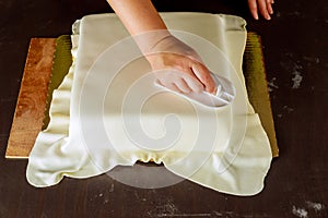 Professional baker cover cake with fondant smoother