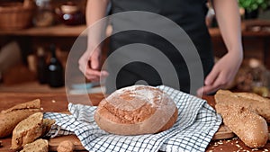 Professional baker putting freshly baked loaf on table in kitchen of country house, old tradition