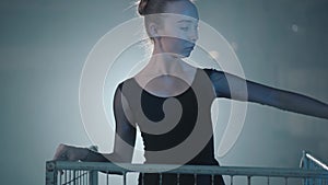 Professional ballerina dancing in black dress in the studio inside the blue cage in spotlight on a black background