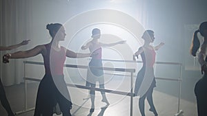 A professional ballerina shows the class ballet moves in a ballroom.