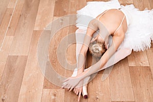 A professional ballerina is sitting on the floor in a dance class.