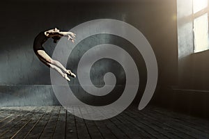 Professional ballet dancer performing in the dark lighted room