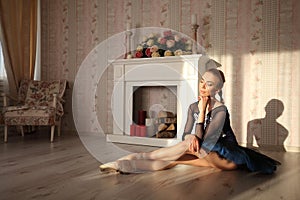 Professional ballet dancer sitting on the wooden floor. Female ballerina having a rest. Ballet concept.