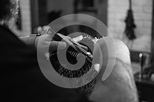 Professional Barber doing hairstyle to his client in barbershop