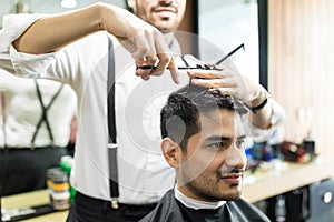 Professional Barber Giving Haircut To Male In Shop