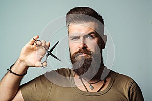 Professional barber man with scissors. Stylish hairdresser in barber shop. Beard styling and cut. Advertising and barber shop