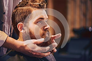 Professional barber styling beard of his client