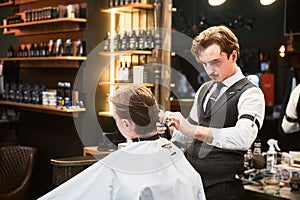 Professional barber using hairspray to finish hairstyle. photo