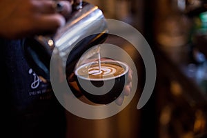 Professional barista draws latte art on coffee cup