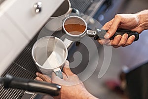 Professional barista with portafilter making coffee