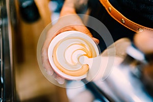 Professional barista pouring latte foam over coffee, espresso and creating a perfect cappuccino