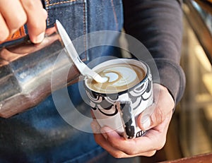 Professional barista pouring latte foame tulip over coffee, espresso and creating a perfect cappuccino