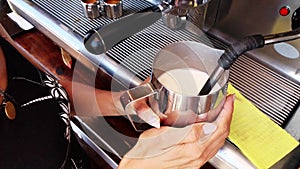 Professional barista prepares a cappuccino in a busy coffee shop