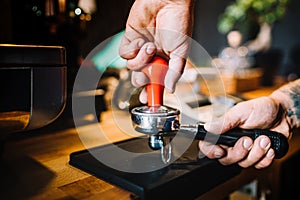 Barista using tamper and pouring freshly brewed cof photo