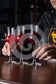 Professional bartender arranging a colorful selection of red cocktails on a wooden counter