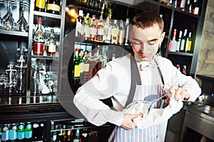 Professional bartender cleaning glass in cocktail bar