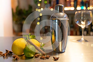 Professional bartender cocktail shaker, bar counter with lemons, limes and species with copy space for text.