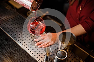 Bartender girl pouring the last straw of a delicious campari cocktail