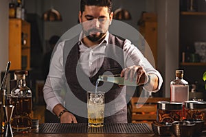 Professional bartender pours cocktail at bar