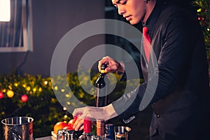 Professional bartender preparing fresh lime lemonade cocktail in drinking wine glass with ice at night bar clubbing counter.