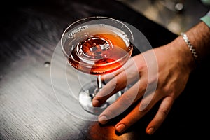 Professional bartender with red cocktail into a martini glass