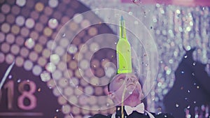 A professional bartender shows an acrobatic show at a disco party with a bottle of delicious alcoholic cocktail