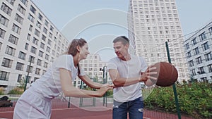 Professional basketball trainer teaches female player. People stand in basketball stand and follow ball. Physical