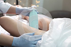 Professional Beautician Applying Soothing Cream on Female`s Legs After Wax Depilation Procedure In Spa