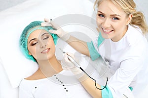 Professional beautician doing eyebrow tattoo at woman face. Permanent brow makeup in beauty salon, closeup. Cosmetolog