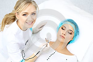 Professional beautician doing eyebrow tattoo at woman face. Permanent brow makeup in beauty salon, closeup. Cosmetolog