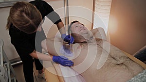 Professional beautician makes waxing to a man in a beauty parlor.