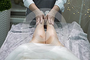 Professional Beautician Massaging Female`s Legs After Wax Depilation Procedure In Spa Salon