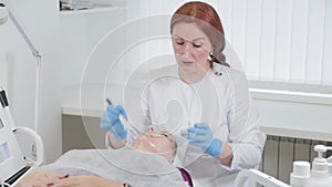 Professional beautician woman applies a mask to the face of a client in a beauty parlor.