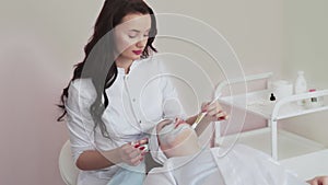 Professional beautician woman applying mask on face with brush to client.