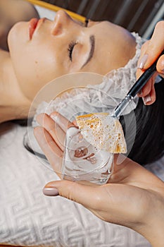 Professional beautician woman stirring mask in glassware.