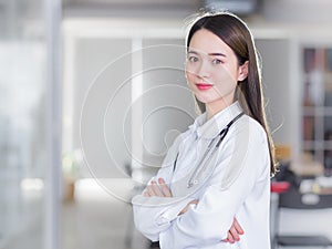 Professional beautiful young woman doctor  standing with arms crossed smiling looking at the camera wearing a white robe and