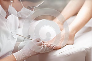 Professional in beauty salon cleaning nails on feet.