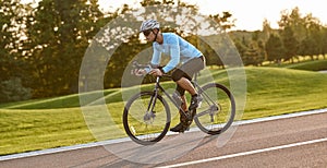 Professional bicycle racer in action. Side view of a young athletic man in sportswear riding mountain road bike at