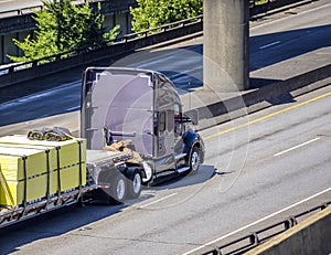 Professional big rig industrial grade semi truck transporting cargo on flat bed semi trailer running on the elevated highway road