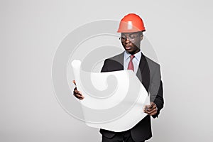 Professional black architect visiting construction site with blueprint plans and protective safety hard hat isolated on white