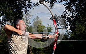 Professional bowman aiming with bow and arrow photo