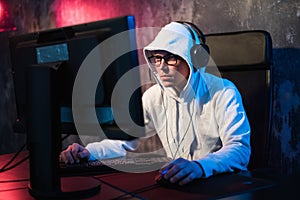 Professional Boy Gamer Plays in Video Game on a eSports Tournament or in Internet Cafe. He Wears Headphones and Speaks photo