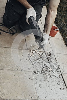 Professional builder in dusty uniform, tile and perforator. Concept overhaul, renovation, redevelopment