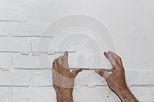 A professional builder installs a new white decorative brick on the wall, close-up