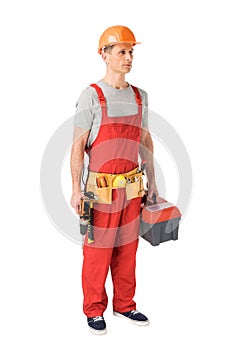 Professional builder in overalls and hardhat holding toolbox and drill