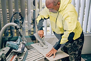 Professional builder smears cement glue on the ceramic tile with a trowel. Concept renovation repair, overhaul, contract