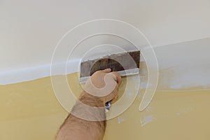 Professional builder smooths wall with spatula putty put on leveled surface of wall