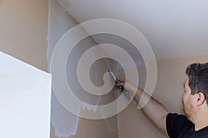Professional builder smooths wall with spatula putty put on leveled surface of wall
